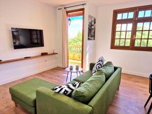 een woonkamer met een groene bank en een televisie bij Jacaranda Azul Icod de los Vinos in Icod de los Vinos