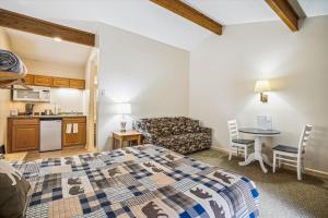 a bedroom with a bed and a table and a kitchen at Cedarbrook Queen Studio 207 in Killington