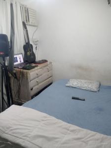 a bedroom with a bed and a dresser with a guitar at Rocinha House in Rio de Janeiro