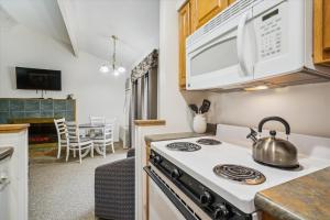 a kitchen with a stove and a microwave at Cedarbrook Deluxe One bedroom Queen Suite with outdoor heated pool 209 in Killington