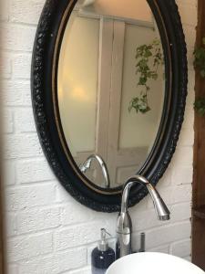 a mirror on a wall above a bathroom sink at Tiny hideaway in Cambridge in Chesterton