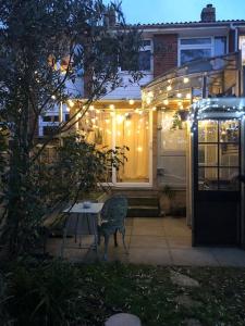 a patio with a table in front of a house with lights at Tiny hideaway in Cambridge in Cambridge