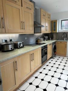 a kitchen with wooden cabinets and a black and white tile floor at The Chill Zone Sleeps 4 in London