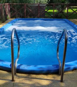 Una piscina azul con dos mangos metálicos. en Studios La Bella Vida en Escobar en Belén de Escobar