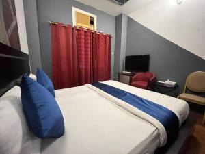 a bedroom with a bed with blue pillows and a red curtain at Bab Al Bahrain Hotel in Manama