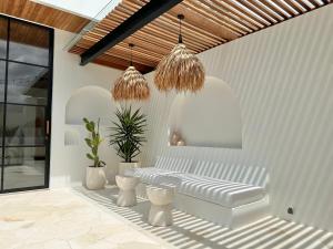 a white room with a bench and two potted plants at The Suites by The Young Villas in Uluwatu