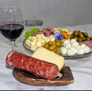 um prato de salsicha e queijo e um copo de vinho em Pousada Laranjeiras Ecoturismo em Bom Jardim da Serra