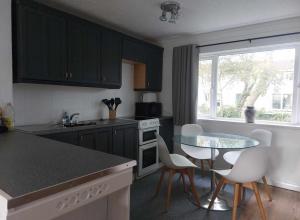a kitchen with black cabinets and a table and chairs at 78 Atlantic Reach in Newquay
