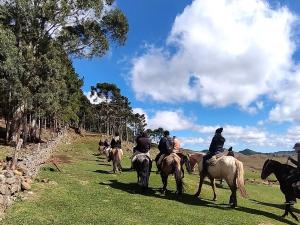 um grupo de pessoas montando cavalos em um campo em Pousada Laranjeiras Ecoturismo em Bom Jardim da Serra