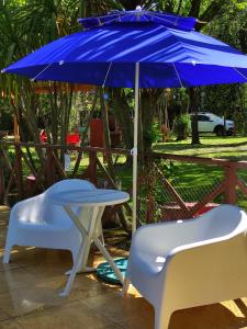 a blue umbrella and two white chairs and a table and a table and chairs at Studios La Bella Vida en Escobar in Belén de Escobar