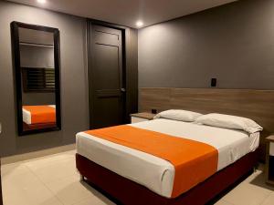Hotel Latino Medellín في ميديلين: غرفة نوم بسرير كبير ومرآة