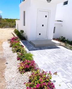 un edificio blanco con flores rosas delante en Thatch Garden Apartment, en Long Bay Village