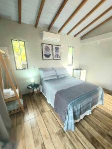 1 dormitorio con 1 cama y suelo de madera en Suíte Ilhinha II em condomínio na Praia do Perequê en Ilhabela
