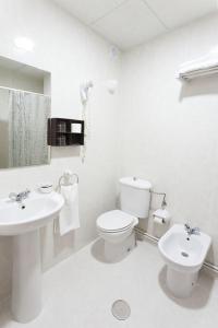 Baño blanco con aseo y lavamanos en Hotel Besaya en Torrelavega