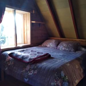 uma cama com um cobertor num quarto com uma janela em Cabañas Rio Sur y tinajas calientes em Puerto Varas