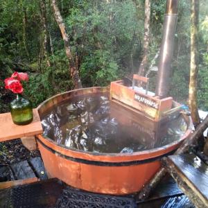 Cabañas Rio Sur y tinajas calientes في بورتو فاراس: حوض استحمام مملوء بالماء بجوار طاولة خشبية