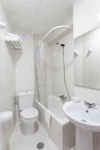 Baño blanco con aseo y lavamanos en Hotel Besaya, en Torrelavega
