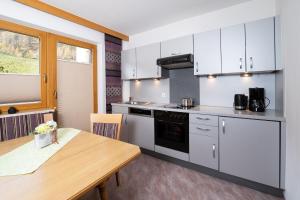 a kitchen with white cabinets and a wooden table at Appartement Rangger in Sölden