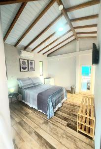 1 dormitorio con 1 cama y suelo de madera en Suíte Ilhinha II em condomínio na Praia do Perequê, en Ilhabela