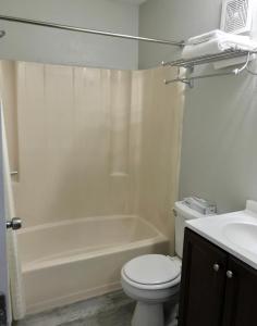 Palace Inn & Suites - Newport News/Jefferson Ave في نيوبورت نيوز: حمام مع مرحاض وحوض استحمام ومغسلة