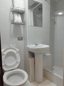 La salle de bains blanche est pourvue de toilettes et d'un lavabo. dans l'établissement Amakonkay Machupicchu, à Machu Picchu