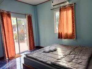 a bedroom with a bed with blue walls and windows at Sappermpool Homestay Buengkhonglong 