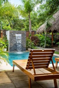 eine Holzbank neben einem Pool mit Wasserfall in der Unterkunft Villa Ave del Paraíso in Playa Avellana