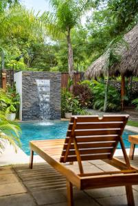 a wooden bench next to a swimming pool with a waterfall at Villa Ave del Paraíso in Playa Avellana