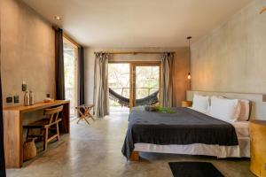 a bedroom with a bed and a desk and a window at Villa Mango Jeri in Jericoacoara