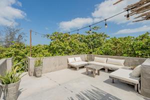 a patio with couches and tables and trees at Villa Mango Jeri in Jericoacoara
