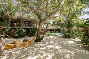 a hammock in front of a house with trees at Villa Mango Jeri in Jericoacoara