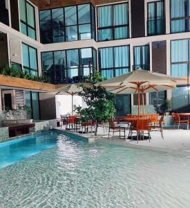 a pool with tables and umbrellas in a building at Sunny Hall Acqua com piscina privativa in Porto De Galinhas