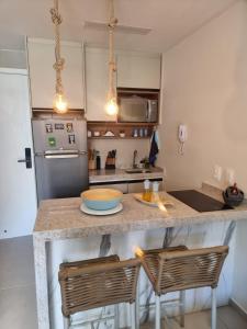 a kitchen with a counter with two chairs at Sunny Hall Acqua com piscina privativa in Porto De Galinhas