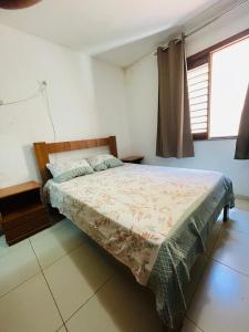 a bedroom with a bed in a room with a window at Aluguel Apto. Triplex Guaramiranga. in Guaramiranga