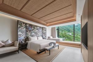 a bedroom with a bed and a couch and a window at Tengchong Jingge Banshan Hot Spring Hotel in Tengchong