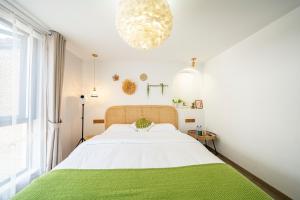 a white bedroom with a large bed with a green blanket at 小喜屋（西井街店） in Qingpu