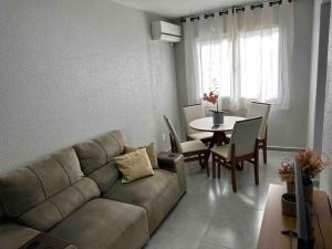 Apartamento há 5 min do Centro de Criciúma. في كريسيوما: غرفة معيشة مع أريكة وطاولة
