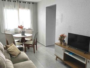uma sala de estar com um sofá, uma televisão e uma mesa em Apartamento há 5 min do Centro de Criciúma. em Criciúma