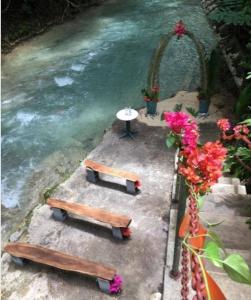 three benches and a table next to a river at Secret Hideaway in Ocho Rios