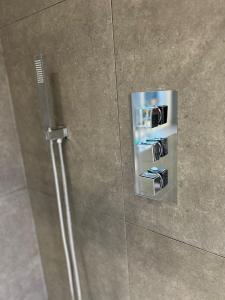 un botón de metal en la pared de una ducha en The Privacy Annex Balham en Londres