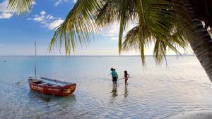 two people standing in the water next to a boat at Confortable apto. en Boca Chica in Boca Chica