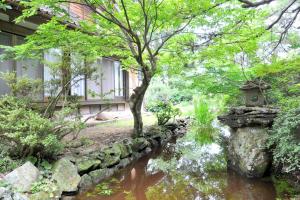 un jardin avec un étang en face d'un bâtiment dans l'établissement Private stay 120years old Japanese-style house, à Okinoshima