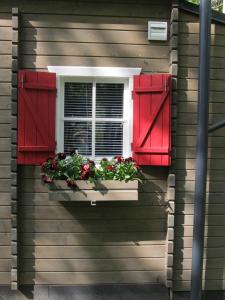 Summerhome في Skulte: نافذة بها مصاريع حمراء وزهور في صندوق النافذة