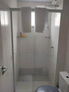 a white bathroom with a shower and a toilet at AP Completo NOVO, com Ar condicionado, internet rápida e Garagem privativa in Paranaguá