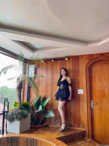 a woman in a black dress standing on a staircase at Khách Sạn Greenhills in Xuan An
