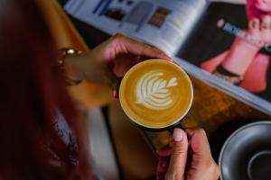 a woman is holding a cup of coffee at Pertiwi Bisma Ubud in Ubud