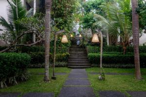 a path in a garden with palm trees and lights at Pertiwi Bisma Ubud in Ubud
