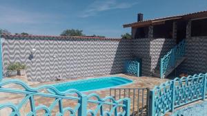 - une piscine avec 2 chaises à côté d'un mur dans l'établissement Casa com piscina, à Mairiporã