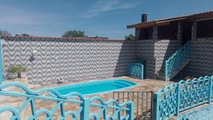 a swimming pool with two chairs next to a wall at Casa com piscina in Mairiporã