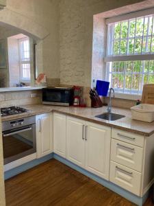 a kitchen with white cabinets and a sink at Villa Jarrow in Christ Church